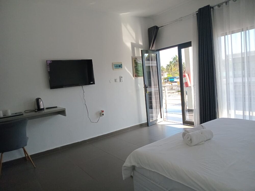 Quarto com cama, secretária, televisão e porta para a varanda