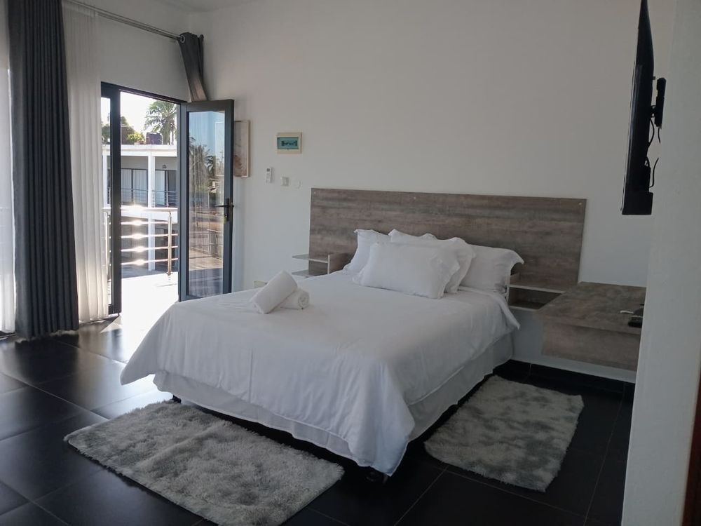 Quarto com cama de casal, televisão e porta para a varanda
