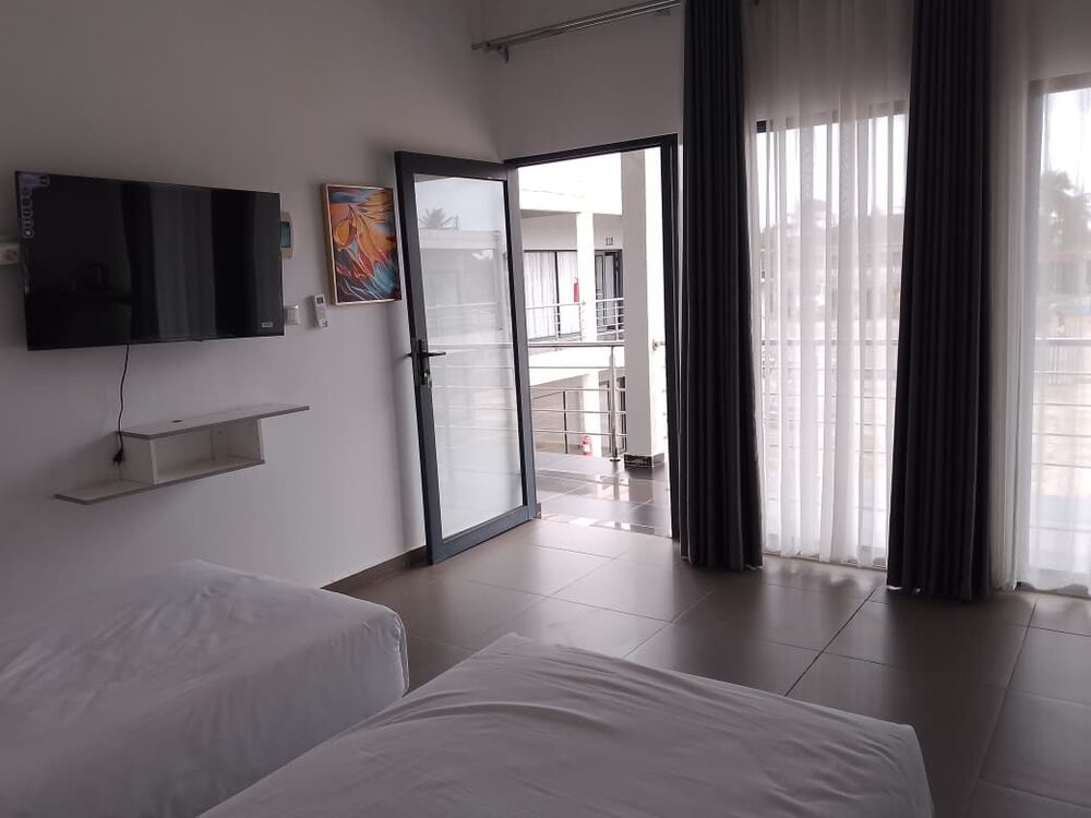 Quarto duplo com duas camas, televisão e acesso à varanda